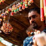 Affordable Souvenirs - A man is looking at a display of colorful beads