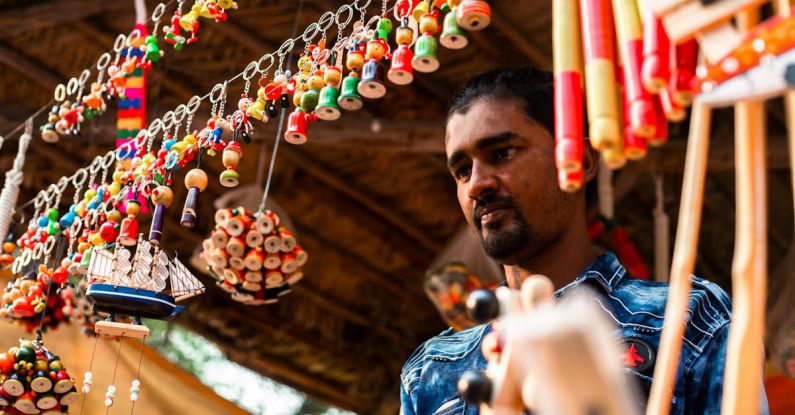 Affordable Souvenirs - A man is looking at a display of colorful beads