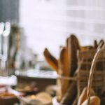 Bakery Cafes - Side view of delicious fresh baked baguette and buns in wicker basket and fresh baked pies and croissant in bakery in daytime