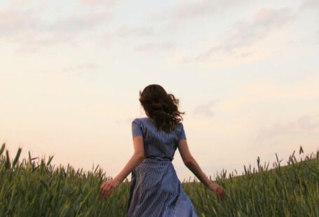 Nature Escape - Woman in Blue Striped Dress Running on the Green Grass Field